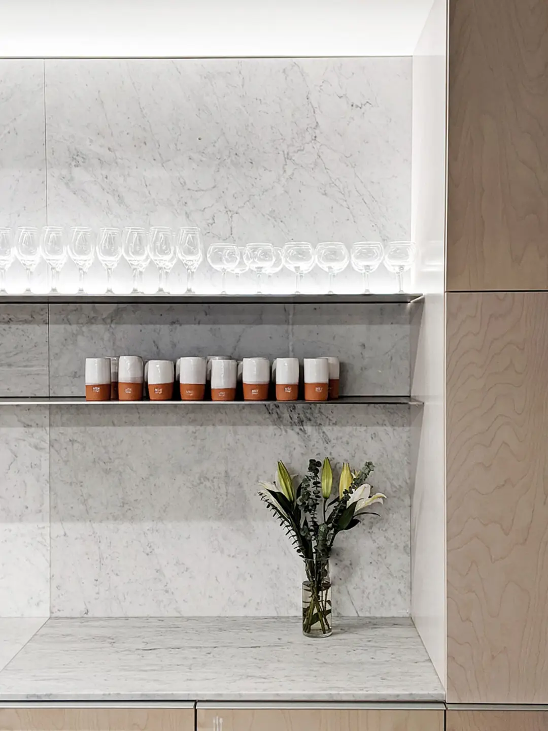  A marble shelf displays a vase of flowers and drinking cups