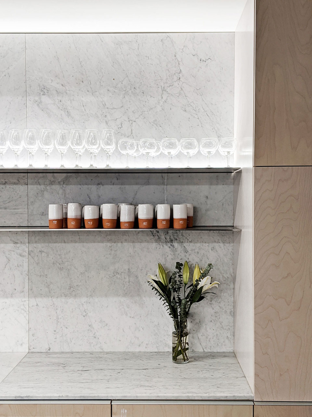  A marble shelf displays a vase of flowers and drinking cups