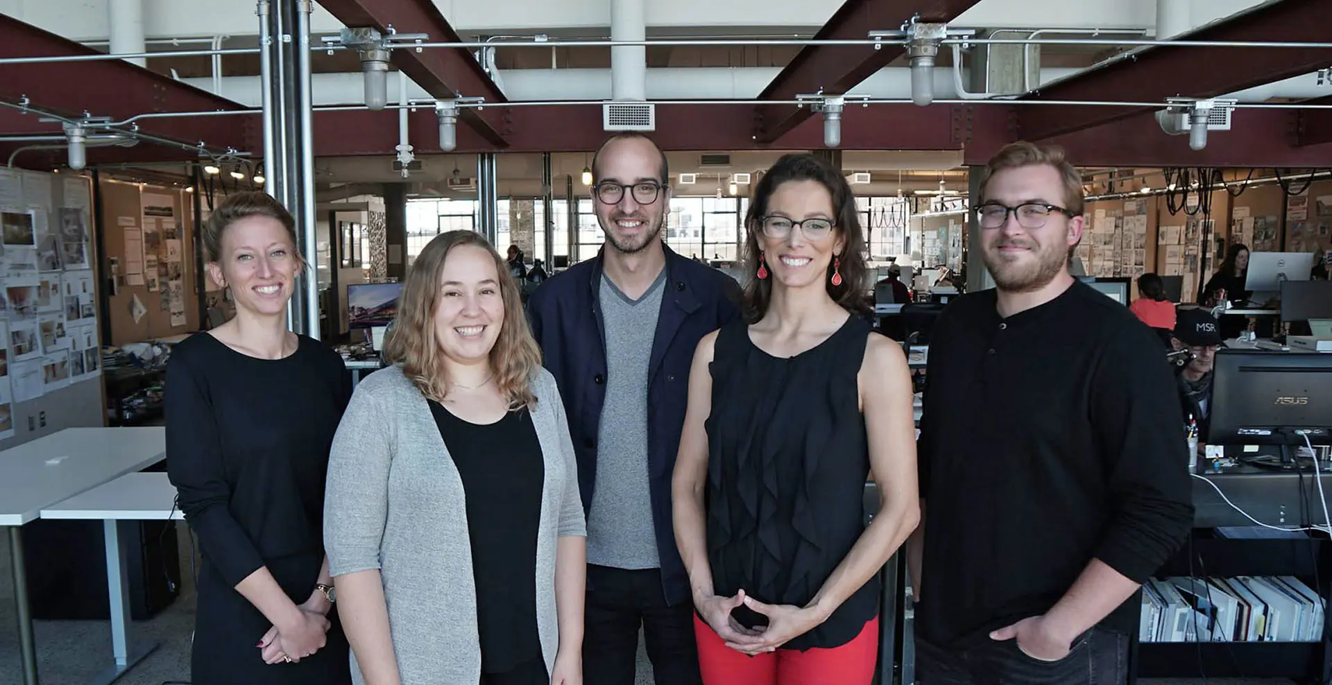 Five people pose together in an office