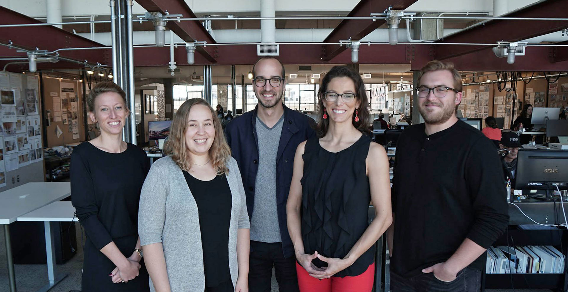 Five people pose together in an office