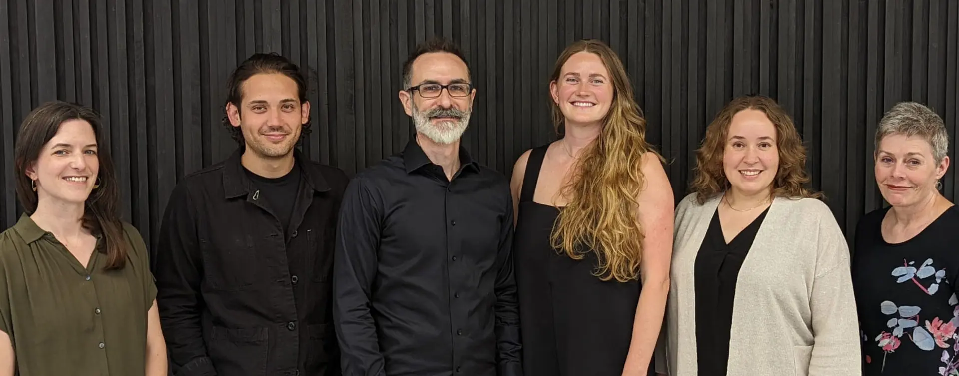 A group of six people smile at the camera